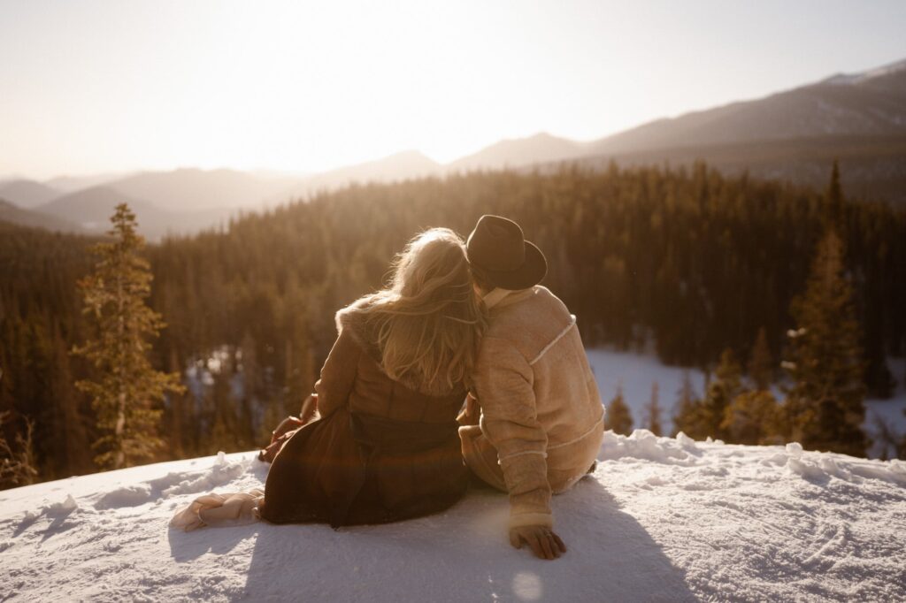 Couple from behind, looking off into the distance over the mountains in Rocky Mountain National Park
