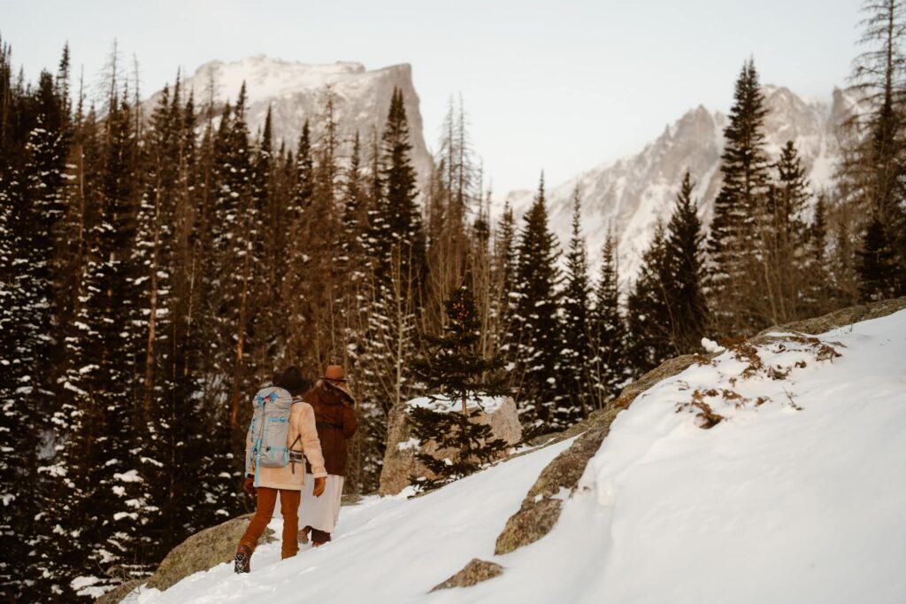 Couple hiking through the snowy mountains about to arrive at Dream Lake in Estes Park