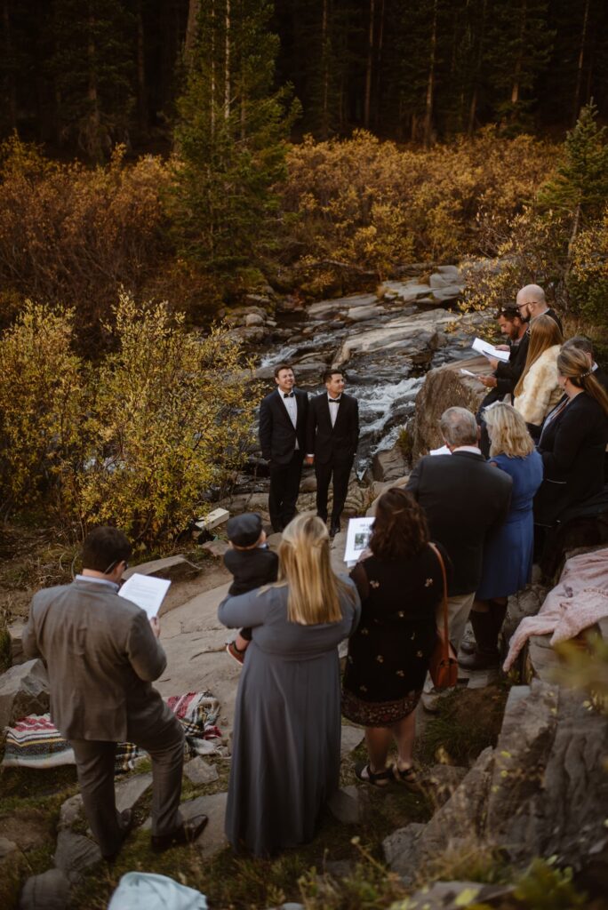 family gathered around couple getting married at a waterfall in Colorado