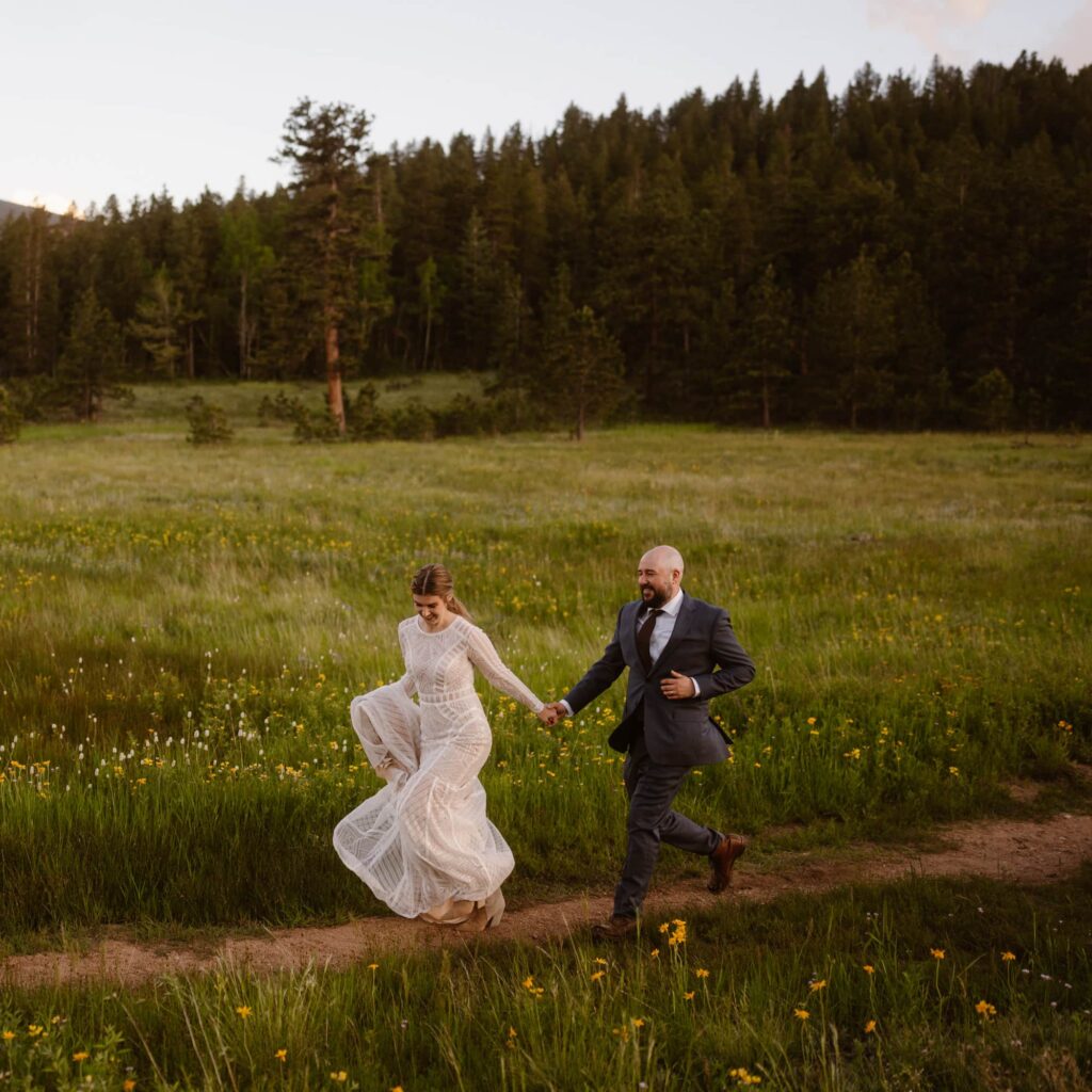 Couple running through a field of wildflowers on their June Colorado elopement day