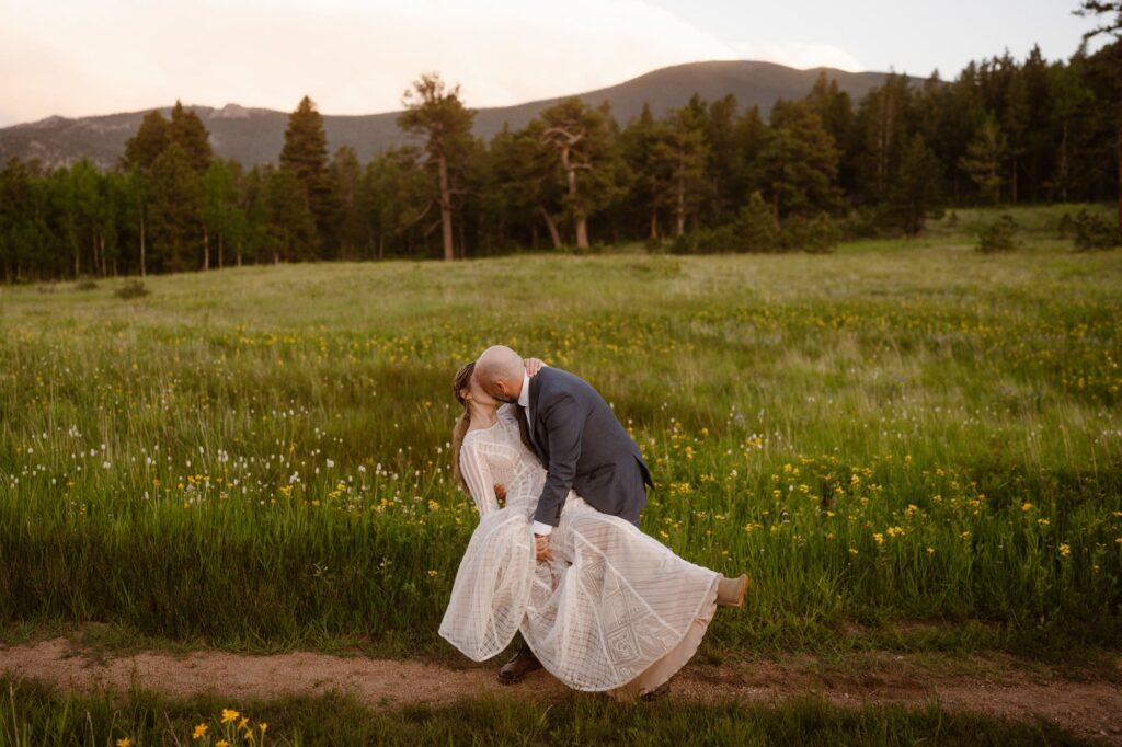 Bride and groom sharing a dip kiss in a mountain meadow