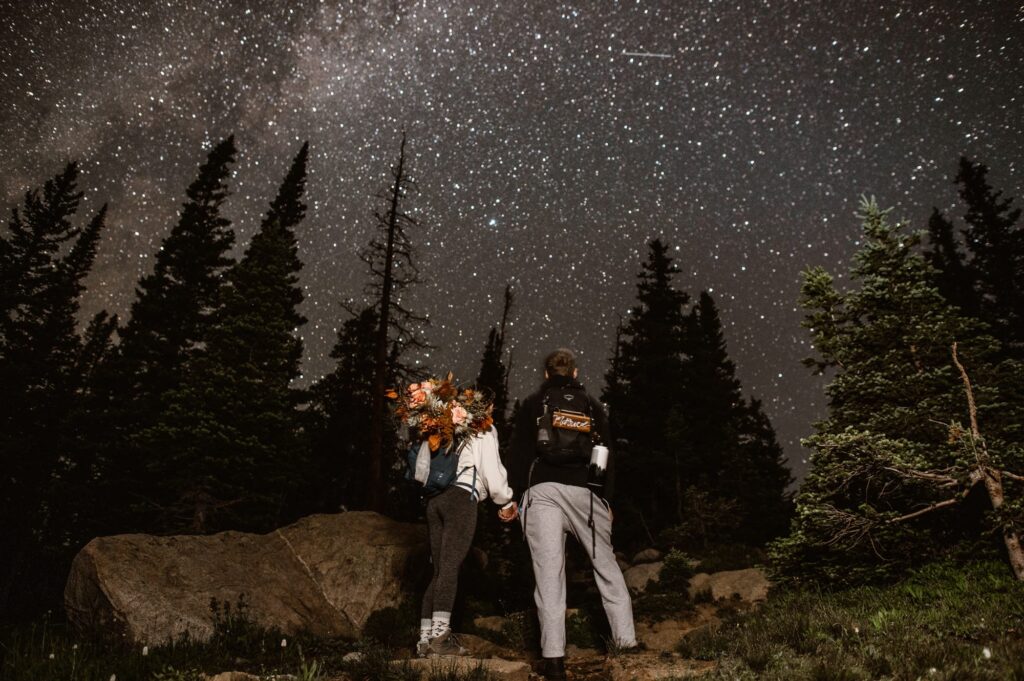 couple standing under the starry night sky on the way to their sunrise hiking elopement