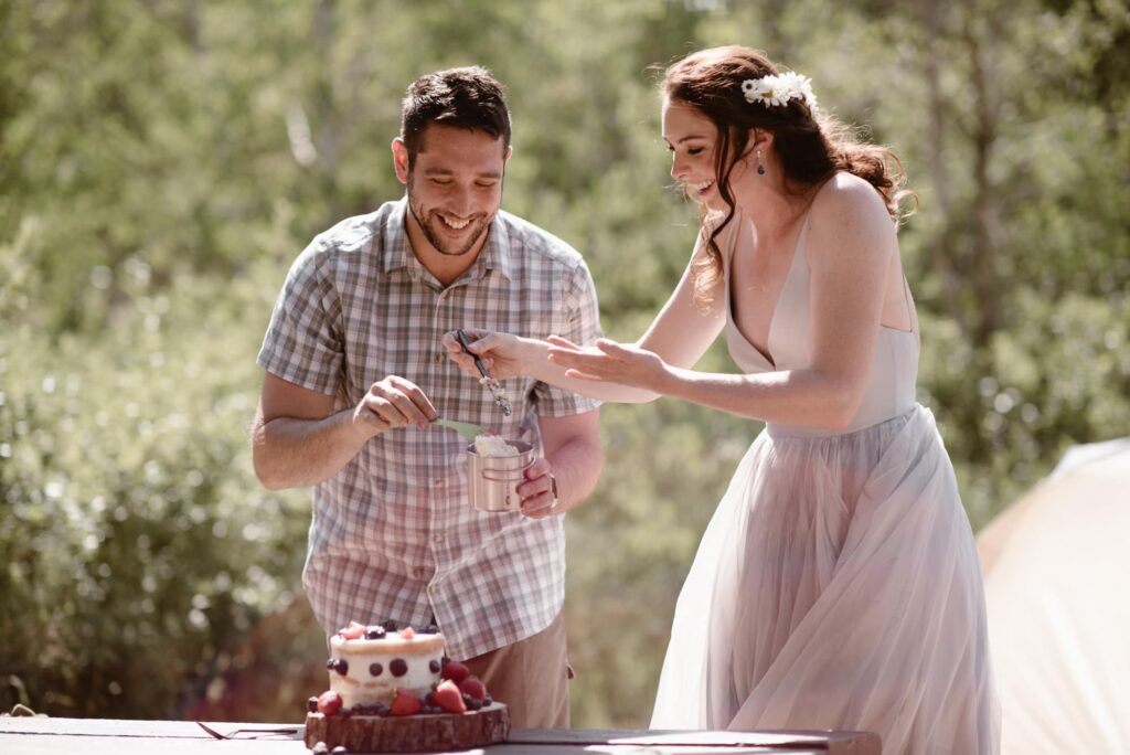 couple eating cake before their wedding at their campsite 