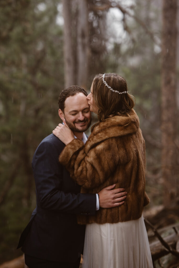 Bride kissing groom on the forehead in a beautiful fur jacket