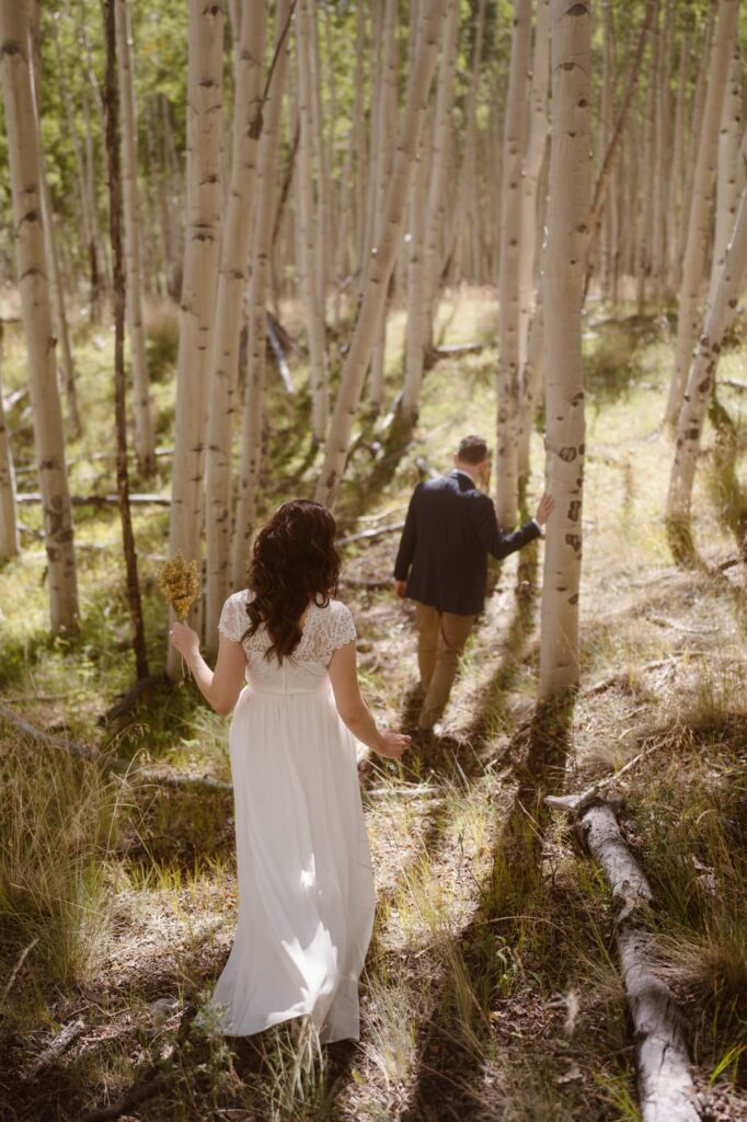 Couple hiking through an aspen grove at adventure elopement