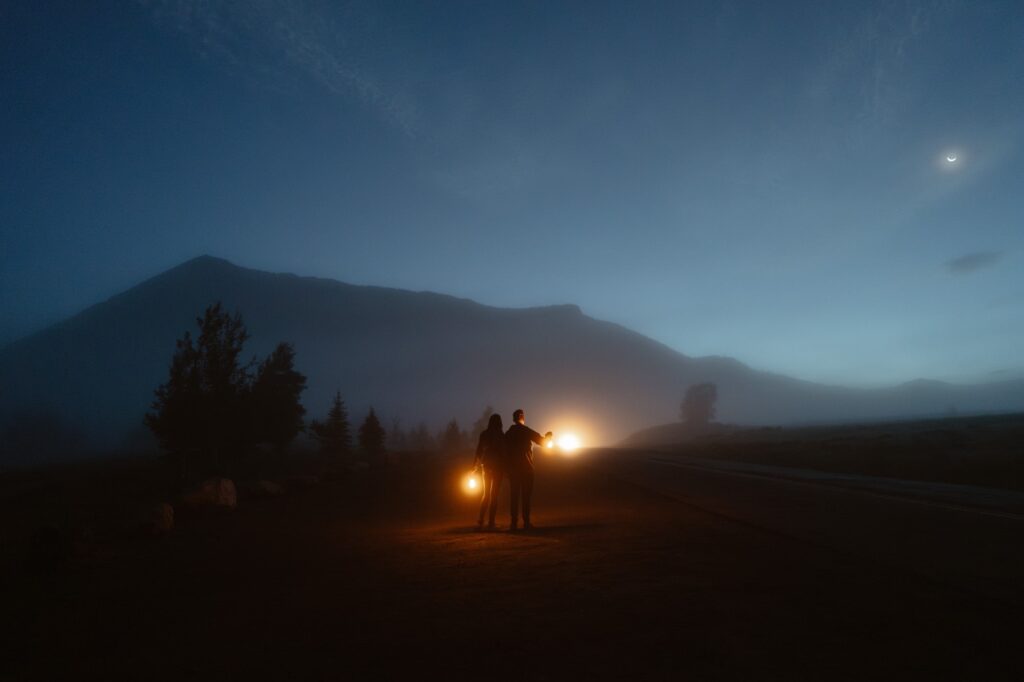 Couple walking under the moon with lanterns in a foggy scene