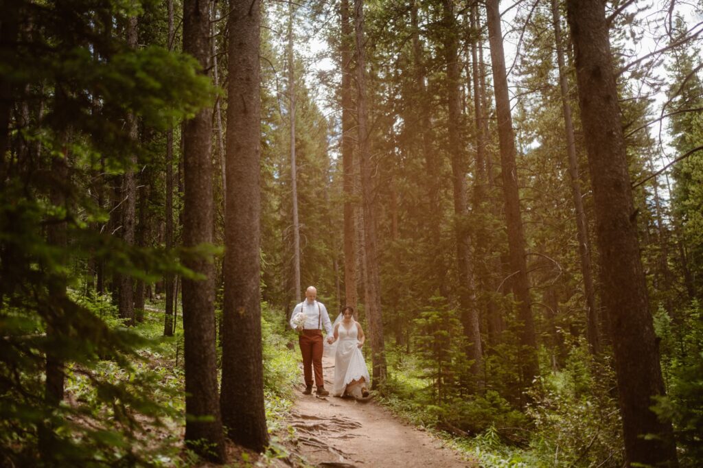 Couple hiking down a trail in their wedding attire