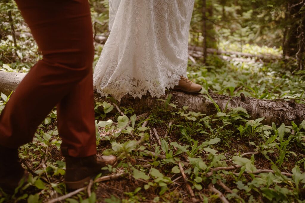 Bride with hiking boots walking down a fallen log