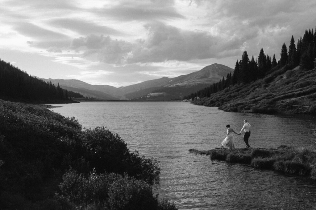 Dramatic black and white image of couple hiking to the lake