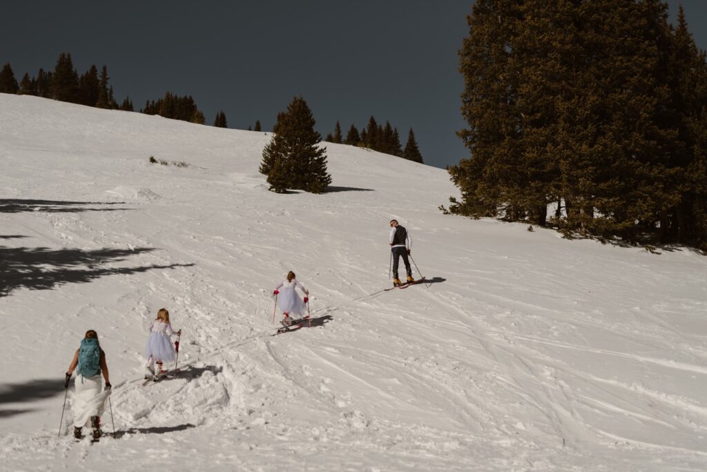 Family skis up a mountain together on their wedding day