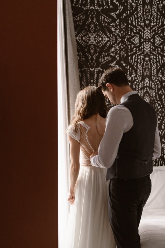 Groom helping bride into her wedding dress