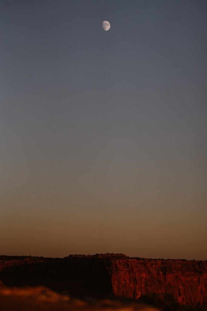 The moon and sunset on red cliffs in Moab Utah