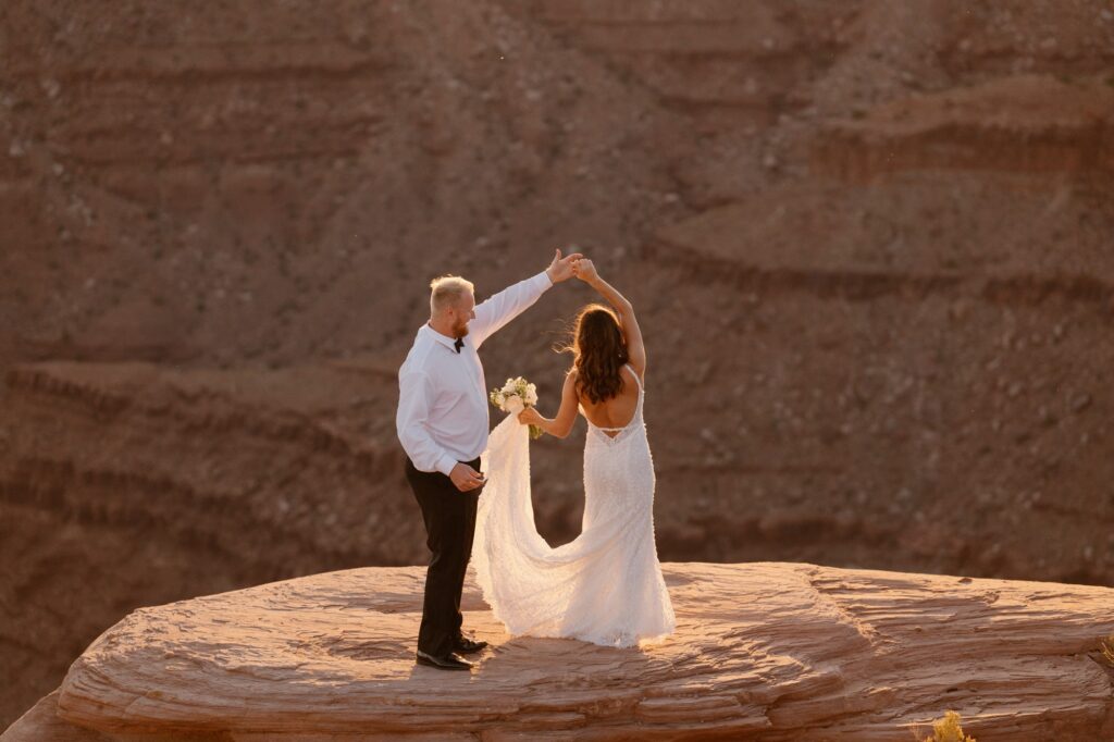 Couple dancing on rocky cliff as the sun goes down