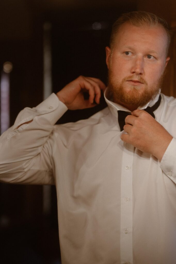 Groom putting on his bow tie