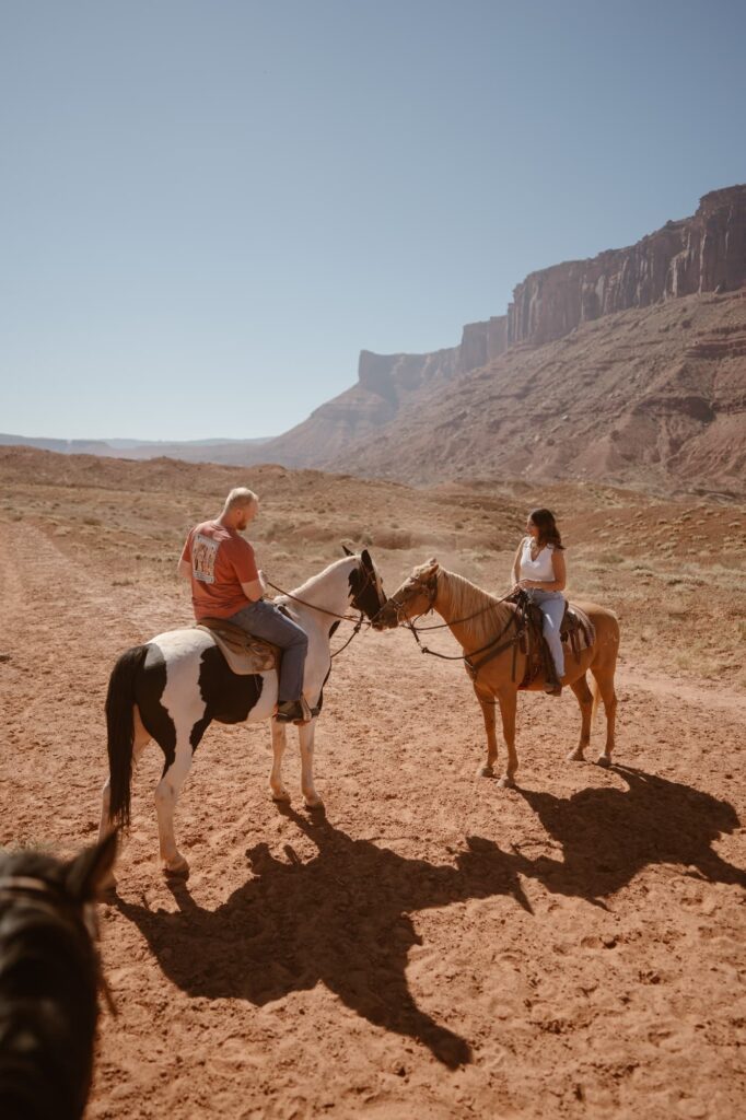 Horses kissing with couple on their back