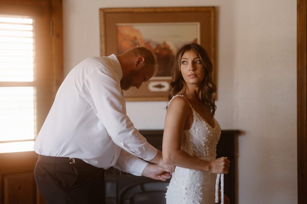 Groom helping bride into her dress at Sorrel River Ranch