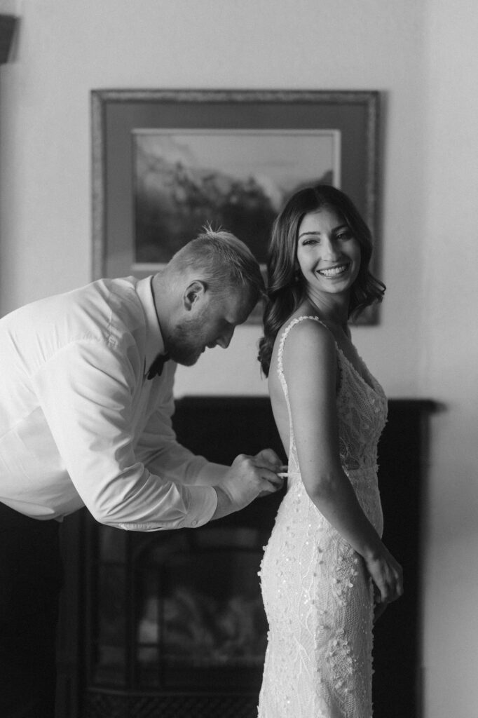 Groom helping bride into her dress