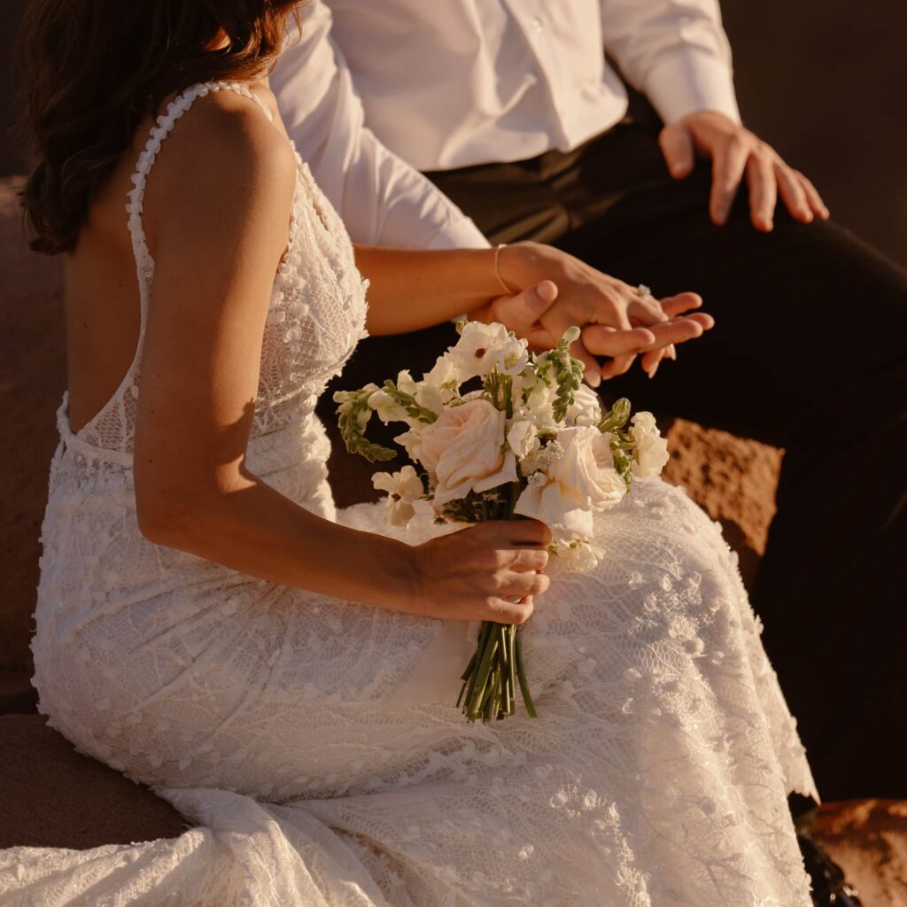 Close up of couple holding hands and flowers
