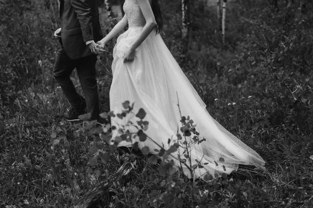 Bride and groom holding hands and hiking through the Colorado mountains