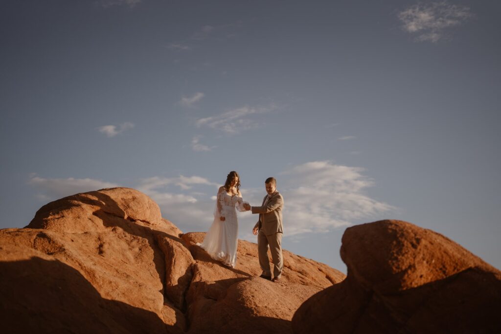 Couple walking down red rocks with a bright blue sky on their wedding day