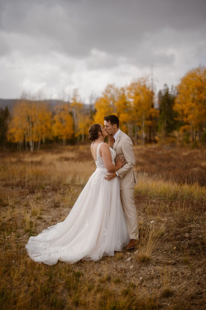 Bride and groom kissing with golden aspen trees in the background