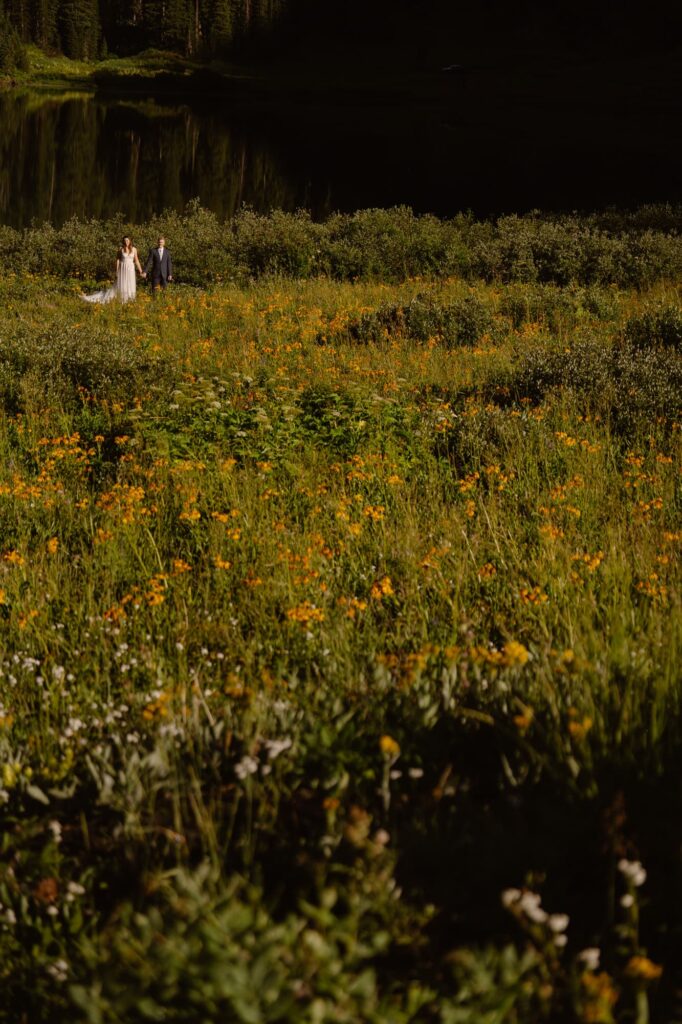 Bride and groom standing in a field of wildflowers