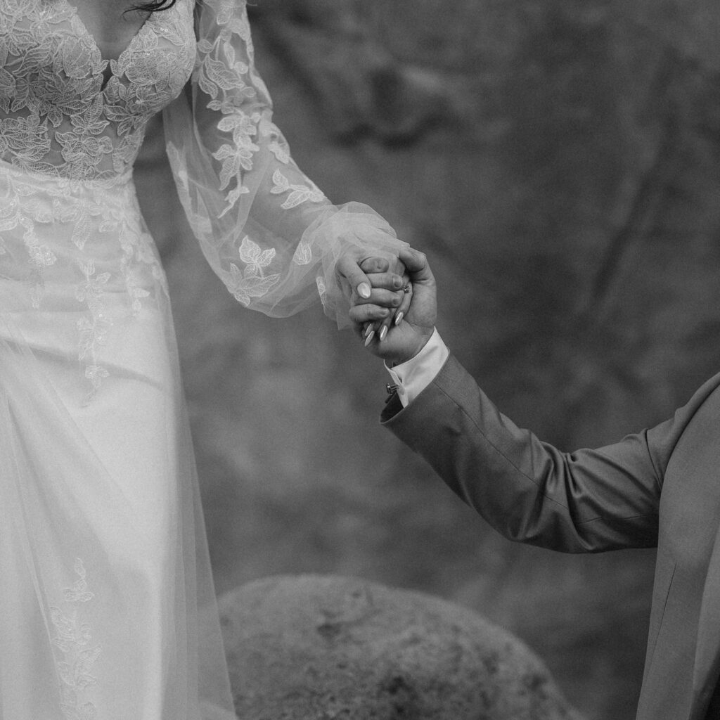 Romantic black and white image of bride and groom holding hands