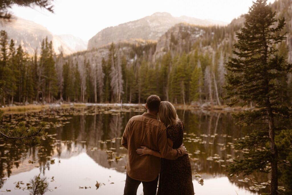 Couple looking at alpine lake in Rocky Mountain National Park at their engagement photos