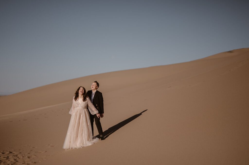 Couple laughing and looking toward the blue sky at Great Sand Dunes National Park