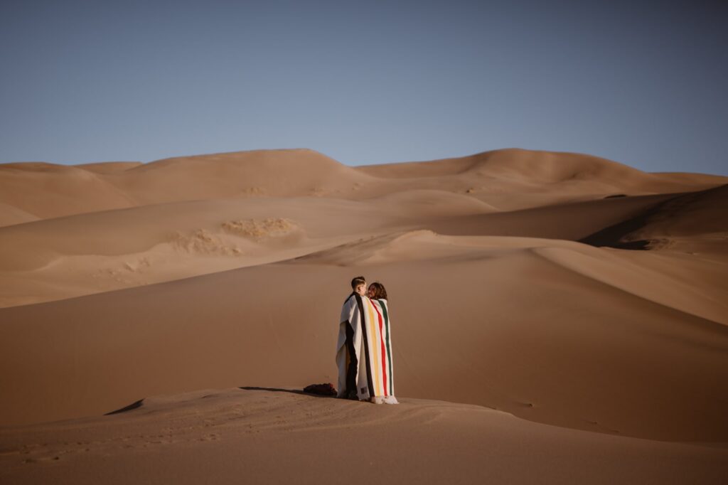 Couple in a blanket on the sand dunes getting married