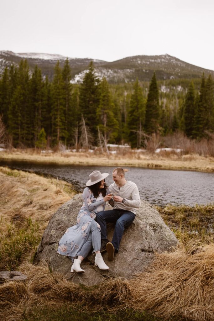 Couple toasting bubbly water to their engagement in the mountains