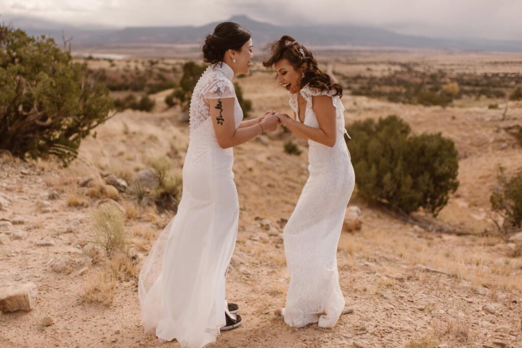 Brides laughing together in the wind on top of a ridge