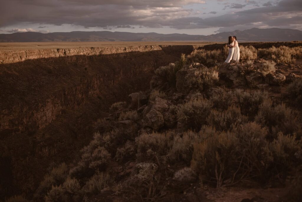 Brides on a cliffside in the desert at sunset