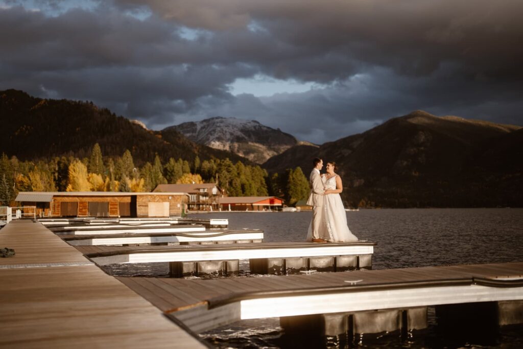 Bride and groom on a lake in the mountains with a moody sunset