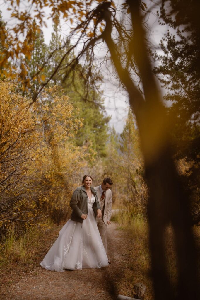 Couple walking through fall foliage on their wedding day