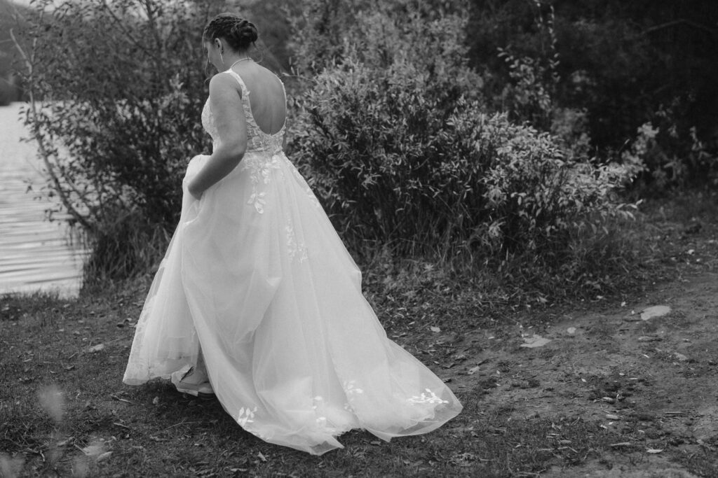 Dramatic black and white photo of bride walking through wilderness
