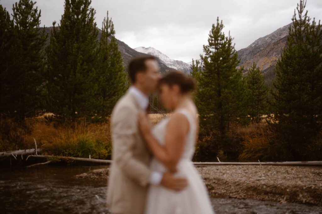 Groom kissing the bride's head with mountains in the distance