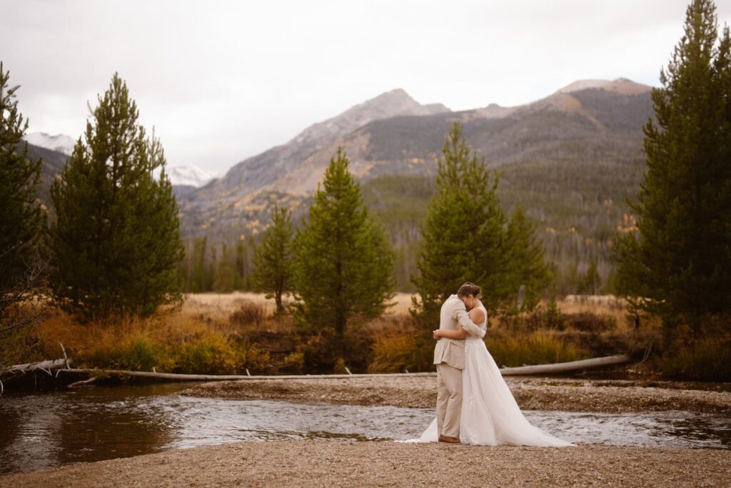 Bride and groom hugging in a beautiful Fall scene in the mountains and along the river
