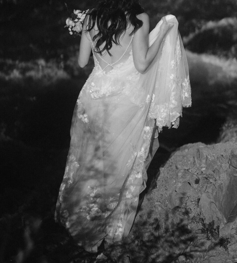 Bride carrying her dress across the stream