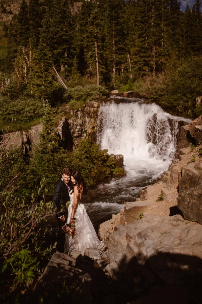 Bride and groom in front of waterfall in Colorado