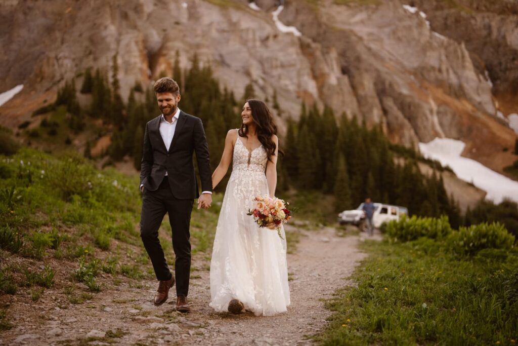 Bride and groom walking away from their Jeep in the Colorado mountains