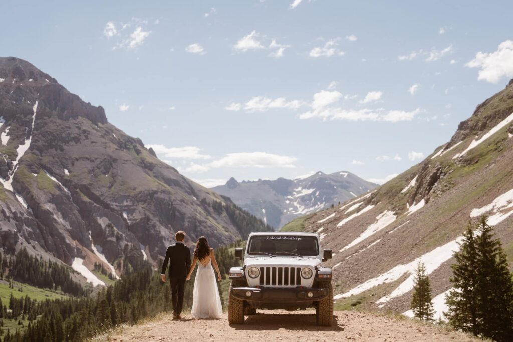 View of mountains, bride and groom and their off-roading Jeep