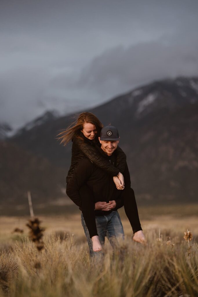 Couple running through a mountain meadow before their wedding