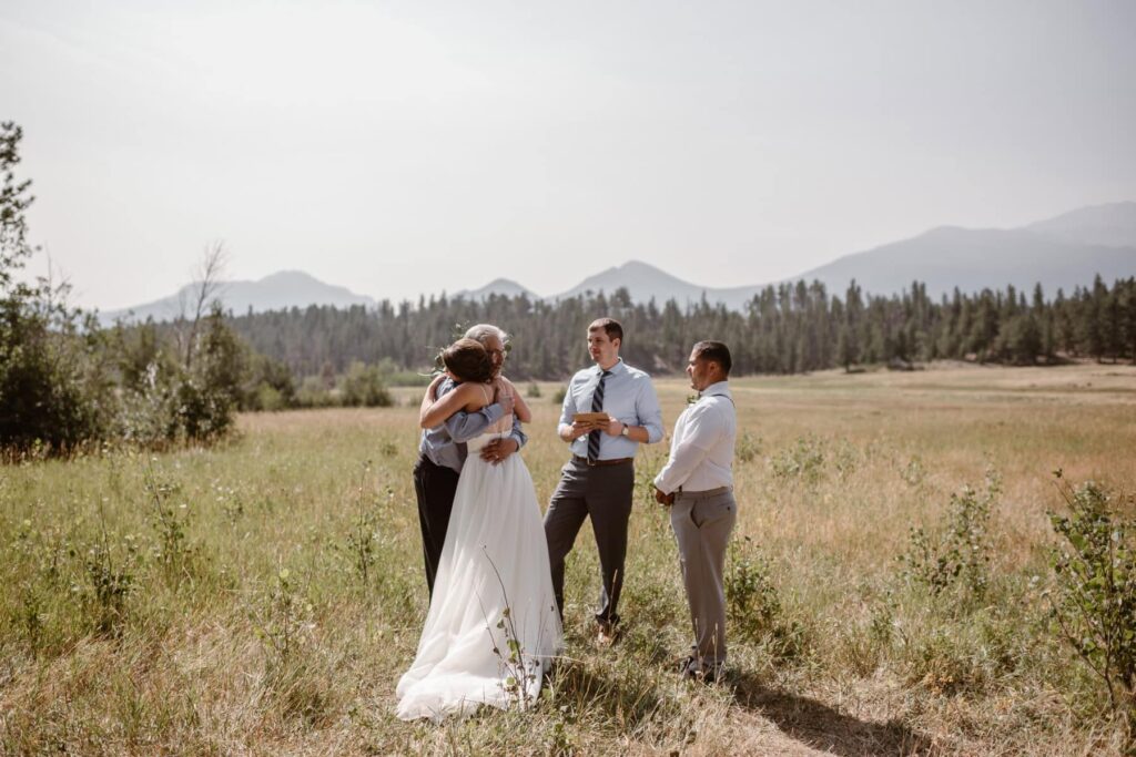 Intimate wedding ceremony where bride is hugging her father in a mountain meadow