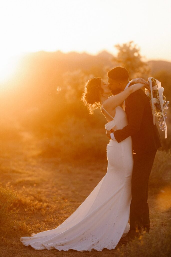 Bride and groom kissing in the desert sunset