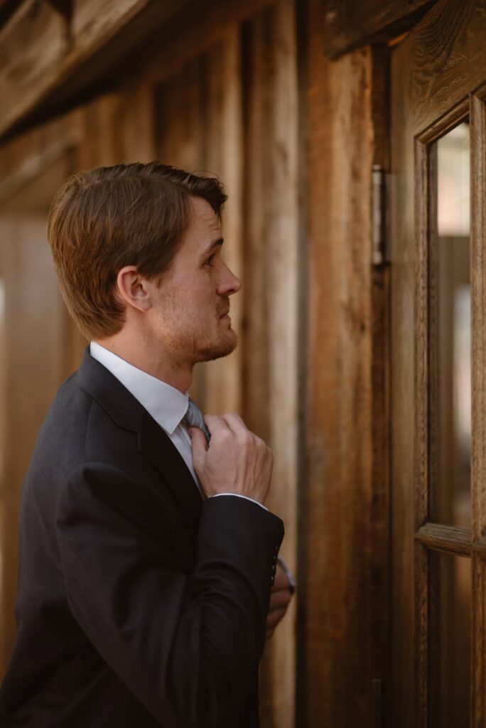 Groom making final touches to blue tie in his blue suit