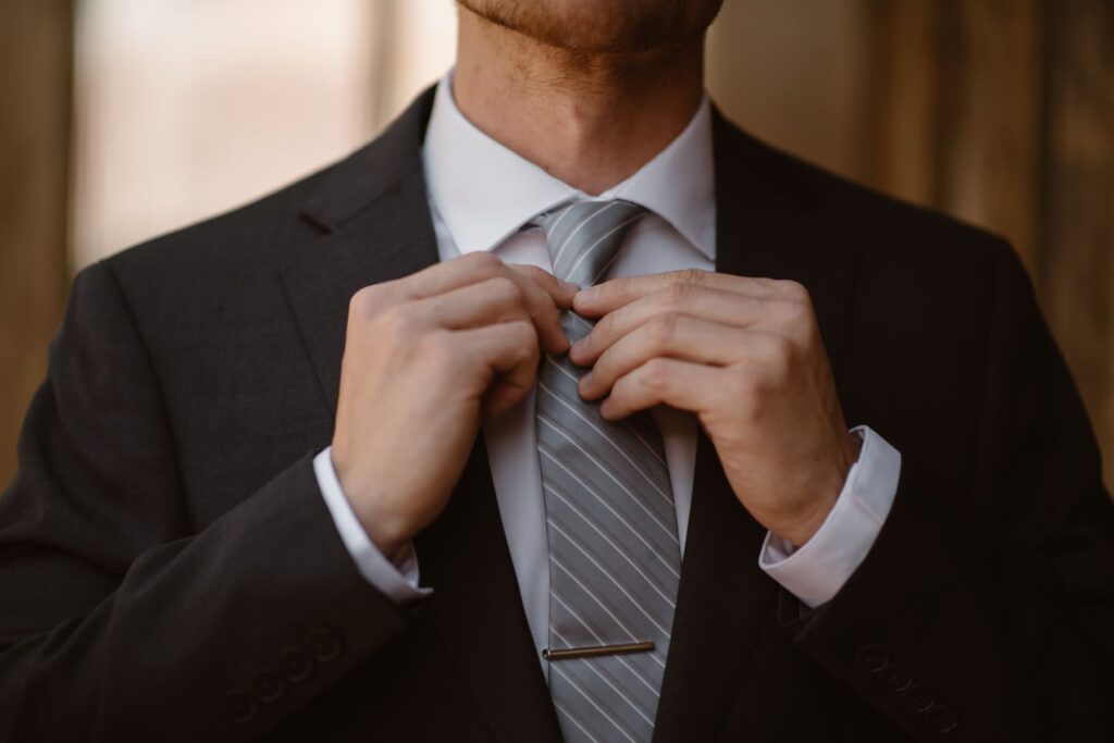 Groom in a blue suit tying his tie