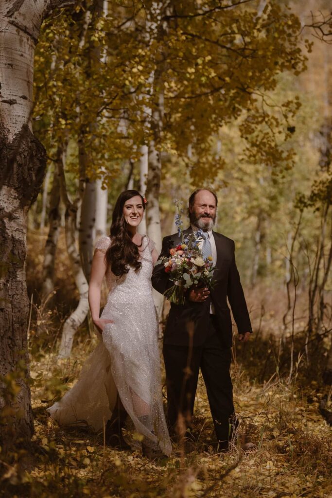 Bride and father of the bride walking down the aspen grove to the wedding site in Crested Butte