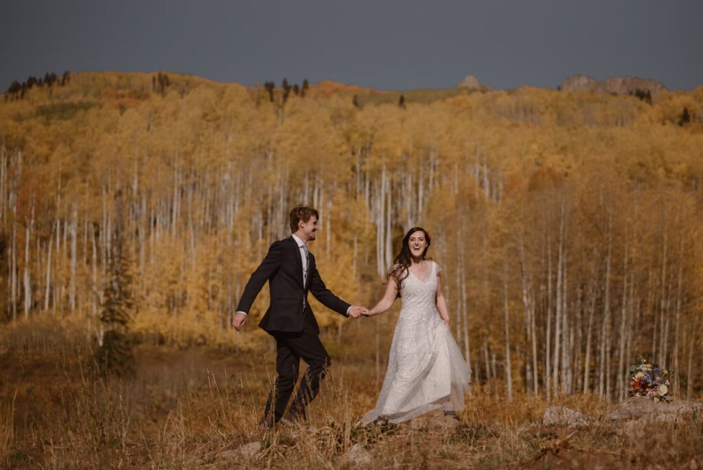 Couple running through a yellow aspen grove in Crested Butte, Colorado