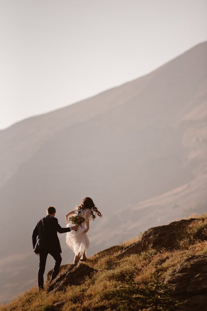 Couple hiking up a mountain ridge in Crested Butte, Colorado on their wedding day